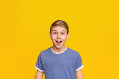 Sürpriz küçük çocuk ağız açık ve gülümseyen tutmak, turuncu stüdyo arka plan