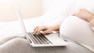 Yatakta yatan bir kadın dizüstü bilgisayar kullanmaya dalmış. Ekrana odaklanmış, yazıp kaydırıyor. Oda loş bir şekilde aydınlatılmış ve o rahat ve rahat görünüyor..