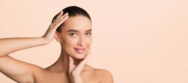 A woman stands with her hands pressed against her cheeks, adding a dramatic effect to her pose. She looks directly at the camera, showcasing a sense of contemplation or surprise. copy space