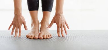 Kırpılmış kadın, bir stüdyoda elleri yoga minderinde ayaklarına değen bir esneme egzersizi yaparken görülüyor. Bir sabah rutini sırasında esneklik ve denge üzerine odaklanılır, panorama, kopyalama alanı