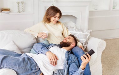 Oturma odasındaki bir kanepede oturan bir erkek ve bir kadın..