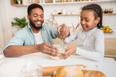 Neşeli Afrikalı baba, sevgili kızına evde gübreyi nasıl karıştıracağını öğretiyor.