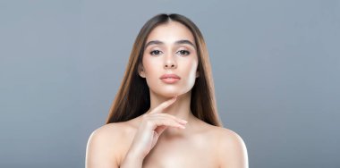 Uzun kahverengi saçlı bir kadın kameraya poz veriyor. Kendine güveni tam bir şekilde duruyor, hafifçe gülümseyerek objektife bakıyor. Saçları omuzlarından dökülüyor.