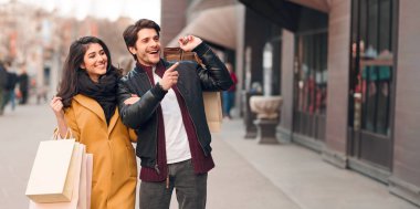 Vay satış. Guy vitrin, modern butikler açık havada alışveriş wih karısı işaret