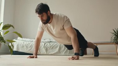 Sabah antrenmanı. Sakallı adam yatak odasında şınav çekiyor.