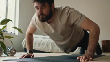 Dayanıklılık eğitimi. Evde şınav çeken sakallı adama yakın çekim.