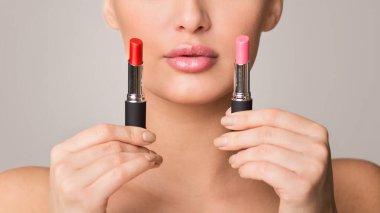 Bir kadın elinde iki ruj tutarken görülüyor. Perdeleri inceliyor ve hangisini kullanacağına karar veriyor. İki makyaj ürününün karşılaştırılması üzerinde duruluyor..