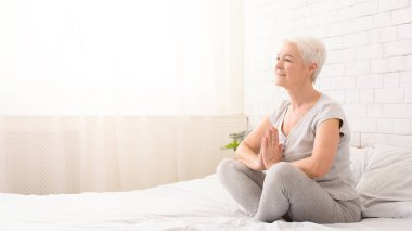 Pratik yoga, Namaste poz yatakta, panorama boş alan ile oturup sakin kadın kıdemli