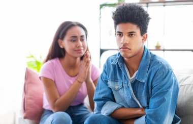 Kolları çapraz bir şekilde kanepede oturan Afro-Amerikalı genç adam kameradan kafasını çeviriyor. Yanında bir kız oturuyor, yalvaran bir ifadeyle ona bakıyor, muhtemelen özür diliyor.