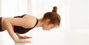 Siyah bluz giymiş bir kadın, güç ve kararlılık göstergesi olarak şınav çekme egzersizi yapar. Vücudu düz bir çizgide uzanıyor, düzgün bir form ve kas gücü gösteriyor..