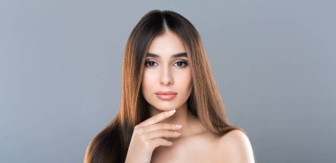 Gri arka planda poz veren, güzel, yarı çıplak bir kadının moda portresi.