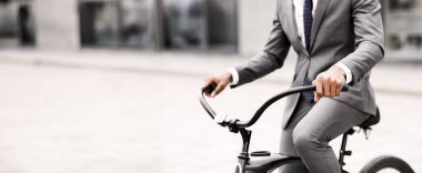 Bir yönetici, şehir merkezinde çalışmak için bisiklet sürüyor. Ruh hali enerjik ve üretken. Modern profesyonel yaşam tarzının özünü yakalıyor.