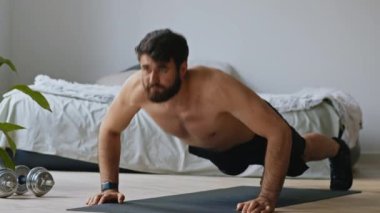 Evde antrenman. Kaslı adam şınav çekiyor, yerde egzersiz yapıyor.