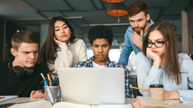 Üniversite kütüphanesinde dizüstü bilgisayar üzerinde çalışan zeki öğrenciler.