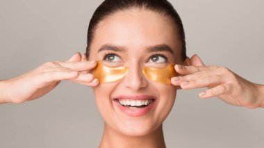 Altın maskeli, yüzünü kapatan bir kadın. Huzurlu bir ifadeyle oturuyor, rahatlama ve gençleşme gösteriyor..