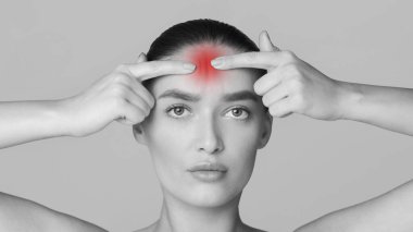 Kafasında kırmızı bir leke olan bir kadın. Yüzünde ciddi bir ifadeyle bir odada duruyor gibi görünüyor..