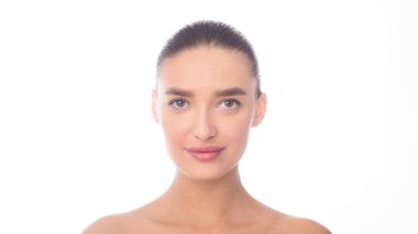 Düz beyaz bir arkaplan karşısında bir kadının yakın plan görüntüsü. Gözleri, burnu, ağzı ve saçı da dahil olmak üzere yüz hatları görülebilir. Kadın fotoğrafta sakin ve sakin görünüyor..