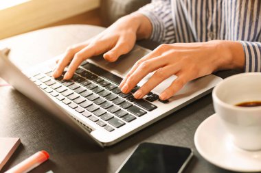 Dizüstü bilgisayarda yazan, takipçileri ile sohbet eden, kafede modaya uygun içerik hazırlayan kadın blogger, boş alan