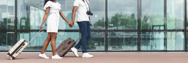 Havaalanı binasının önünde el ele yürüyen bir çift. Her biri tekerlekli bavul taşıyor. Sıradan kıyafetler giyiyorlar, fotokopi odası.