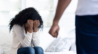 Bir kadın kanepede oturur, kafası ellerinin arasında ağlarken, bir adam arkasında durur..