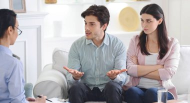 Bir adam ve bir kadın bir danışmanlık seansında bir danışman ile sohbet ediyorlar. Meseleleri sakin ve profesyonel bir ortamda tartışırken odaklanmış ve dikkatli görünüyorlar..