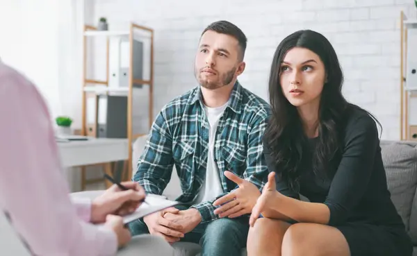 stock image A young couple sits attentively in front of a therapist, seeking guidance and support during a counseling session. The woman gestures with her hand while the man listens intently