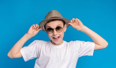 Güneş gözlüğü ve hasır şapka, mavi panorama arka plan neşeli şık çocuk Portresi