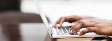 Close-up shot of a persons hands typing on a laptop keyboard.