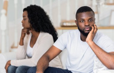 Bir erkek ve bir kadın ayrı koltukta oturur, düşünceli bir ifadeyle aşağı bakarlar..