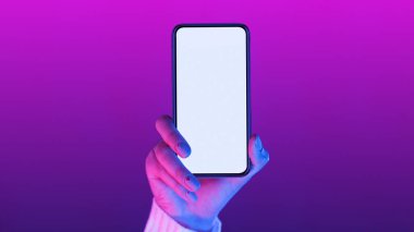 Beyaz ekranlı telefonu tutan bir kadın eli. Arkaplan tarafsız, kadına ve telefona odaklı, model, kopyalama alanı, kırpma