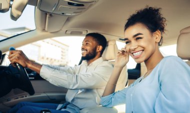 Neşeli genç siyah çift güneşli ve güneşli bir günde arabalarıyla gezintiye çıkıyorlar. Adam direksiyonu tutarken kameraya gülümsüyor. Kadın yolcu koltuğunda oturuyor.