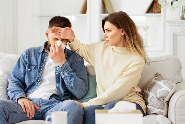 Woman Taking Care Of Her Ill Husband, Touching His Forehead