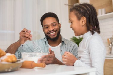 Mutlu Afrikalı baba, şirin küçük kızına Hamur 'u nasıl karıştıracağını gösteriyor, mutfak içi, kopyalama alanı