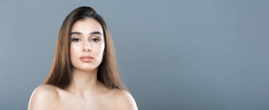 Uzun kahverengi saçlı bir kadın fotoğraf için poz veriyor. Kameranın önünde kendinden emin duruyor, dalgalı kilitlerini ve zarif duruşunu sergiliyor, boşluğu kopyalıyor.