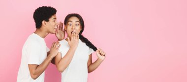 Boyfriend pembe arka plan üzerinde sürpriz kız ilginç dedikodu fısıldayan