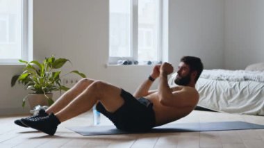 Karın kası egzersizi. Genç adam mekik çalışıyor, evde karın kaslarını çalıştırıyor.