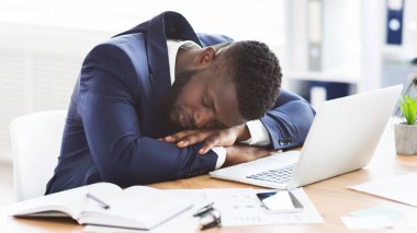 Yorgun Afrikalı Amerikalı genç iş adamı ofisinde uyuyor, aşırı çalışma konsepti, fotokopi alanı ile panorama
