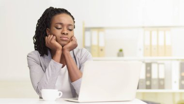 Sıkılmış siyahi bir kadın profesyonel ofiste bir bilgisayar üzerinde çalışıyor. Sahne dağınık bir masa ve sıkıcı bir dekor ile, onun iş yerindeki ilgisizliğini ve yorgunluğunu vurguluyor..