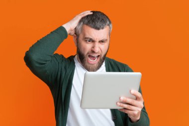 Elinde tablet tutarken yüzünde şaşırmış bir ifade olan bir adam, muhtemelen cihazda gösterilen beklenmedik haberlere ya da bilgilere tepki veriyor..