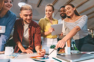 Genç tasarımcılar çizimler için fikirleri tartışıyor ve paletlerden renkler seçiyorlar