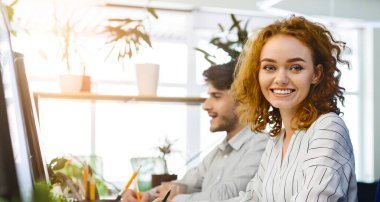 Ofiste sevimli kızıl saçlı kadın portresi, kamera gülümseyen, boş alan ile panorama