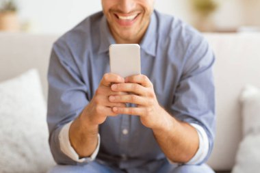 Mutlu Adam Telefonda Mesaj Atıyor. Evde Kanepede Oturan Akıllı Telefonda Oynayan Adam