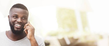 Modern ofis ortamında cep telefonuyla konuşan bir adam gülümser..