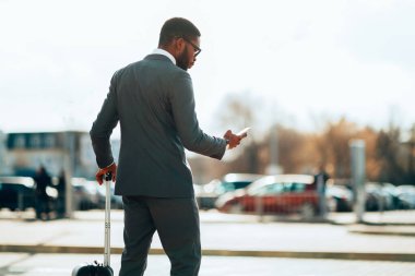 İş adamı taksi sipariş, cep telefonu uygulaması kullanarak, havaalanında gelen
