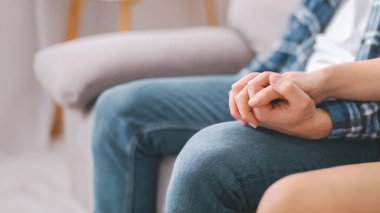 Kapalı bir koltukta otururken çiftlerin ellerinin birbirine sıkıca kenetlendiği yakın plan bir fotoğraf. Görüntü, anın samimiyetine ve iki birey arasındaki bağlantıya odaklanır..