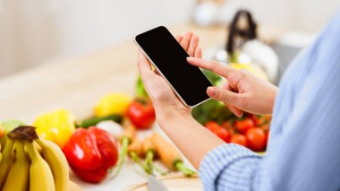 Tarifi Ara. Evde Sağlıklı Salata Pişirmeye Hazırlanan Akıllı Telefonu Kullanan Kadın