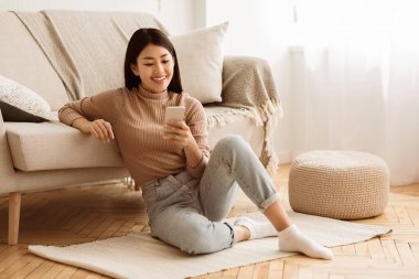 Mutlu Asyalı Kız Evde Telefonda Mesajlaşma, Kanepe yakınında Katta Oturan