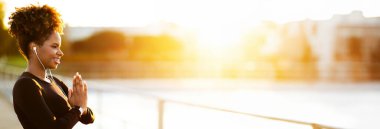 Sağlık Konsepti. Açık havada meditasyon yapan rahat siyah kadın portresi, aktif giyimli Afro-Amerikan bayan, Namaste jestleri yapıyor, dışarıda antrenmanlardan keyif alıyor,