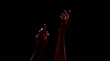Bu resim, bilinmeyen bir ışık kaynağı tarafından aydınlatılan, görünmeyene doğru uzanan iki eli gösteriyor. Elleri koyu bir arka planda siluete bürünmüş.
