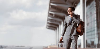 Gezgin İşadamı. Afrikalı Adam Havaalanında Telefonda Konuşuyor ve Bagajla Yürüyor